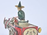 a small toy horse pulling a cart with a man on it