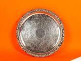 une assiette en argent posée sur une surface orange avec un fond blanc