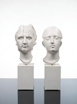 deux sculptures blanches représentant des têtes sont posées l'une sur l'autre