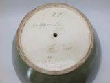 a green vase with writing on it sitting on a table