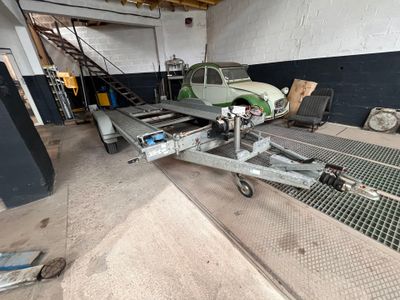 a small green car on a trailer in a garage