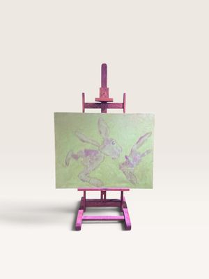 un petit chevalet sur lequel est posé un tableau, posé sur une surface blanche