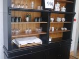 a black china cabinet with a lot of dishes and glasses on it