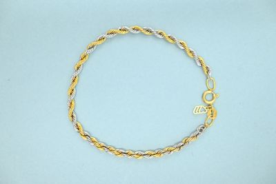 a close up of a gold and silver bracelet on a blue surface