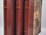 trois livres en cuir marron empilés les uns sur les autres sur une surface blanche