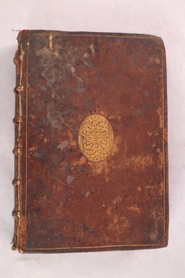 un vieux livre marron orné d'un médaillon doré sur la couverture
