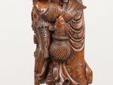 wooden statue of a man holding a bird and a bird perched on a branch