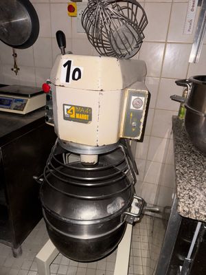 une photo d'un mixeur dans une cuisine où se trouvent de nombreuses casseroles et poêles