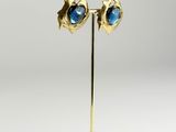 a pair of gold and blue stone earrings on a stand