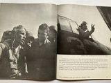 an open book with a picture of a man and a woman in front of an airplane