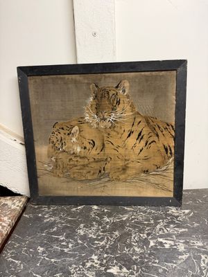 tableau représentant un tigre se reposant par terre devant un mur blanc
