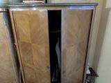 une armoire en bois dont la porte est ouverte, dans un coin de la pièce