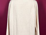 a white sweater on a mannequin stand against a red wall