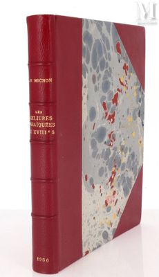 un vieux livre à la couverture rouge posé sur une table blanche