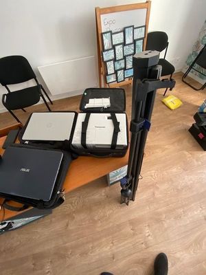 a desk with a laptop, a camera, a monitor, and a tripod on it