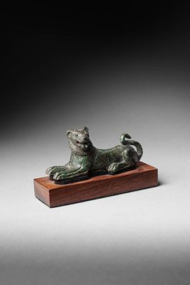 une statue en bronze représentant un chat, posée sur un socle en bois