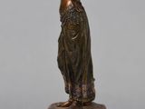 an image of a bronze statue of a woman standing on a marble base