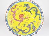 une assiette jaune ornée d'un motif représentant un dragon