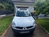 une petite camionnette blanche garée devant une maison