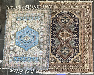 deux tapis orientaux posés sur un sol carrelé, à côté d'un tapis bleu et blanc