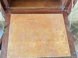 a wooden cabinet with a door open on a tile floor