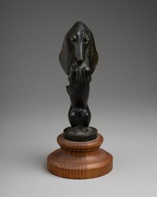 a bronze statue of a dog on a wooden base