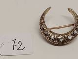 une photo d'une broche en forme de croissant en or, sertie de diamants