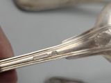 a person holding a spoon and a fork in front of a group of spoons