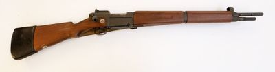 un vieux fusil avec un canon en bois sur une surface blanche