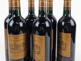 four bottles of wine are lined up in a row on a white surface