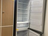 an empty refrigerator in the corner of a room with a bed