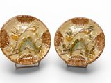pair of gold plate with birds and flowers on them on a white surface
