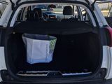 the back of a white car with its trunk open and a bag in the trunk