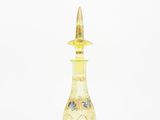 a yellow glass bottle with a gold top sitting on top of a white surface