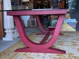 a pink table with a glass top in the middle of a room