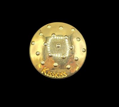 GUERLAIN Broche circulaire en métal doré, modèle "Kiss Kiss"…