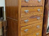 a tall wooden chest of drawers in the corner of a room