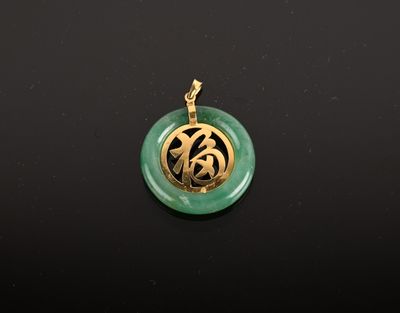 gros plan d'un pendentif vert et or sur une surface noire