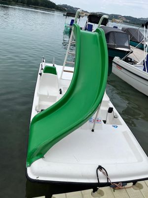 a green slide on the back of a boat in the water
