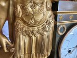 a gold statue of a man holding a clock