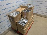Plusieurs cartons contenant des pièces métalliques diverses sont empilés sur une palette