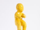 a small yellow figurine sitting on a white surface