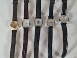 five different watches are lined up on a white surface