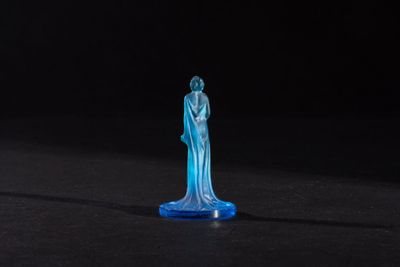 a blue glass statue of a woman standing on a black surface
