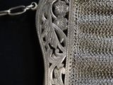 a silver purse with a chain around it on a black surface