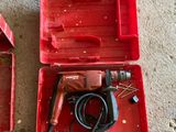 a red tool box with a drill in it and a pair of brown shoes