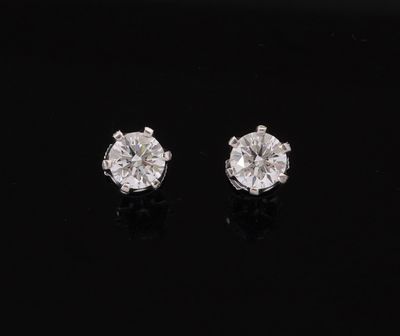 a pair of diamond earrings on a black surface