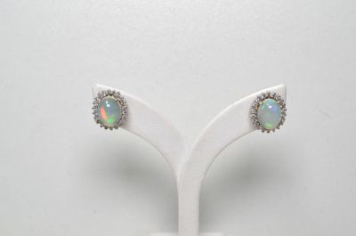 une paire de boucles d'oreilles en oplite et diamants, présentée sur un présentoir blanc