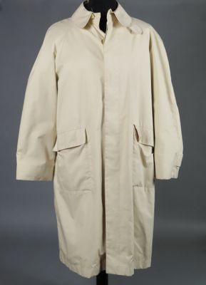 une blouse blanche posée sur un mannequin, sur fond gris