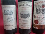 three bottles of red wine are lined up on a pink background